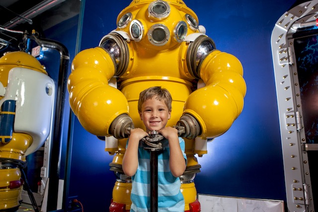 A boy posing with a diving suit in the History of Diving Museum
