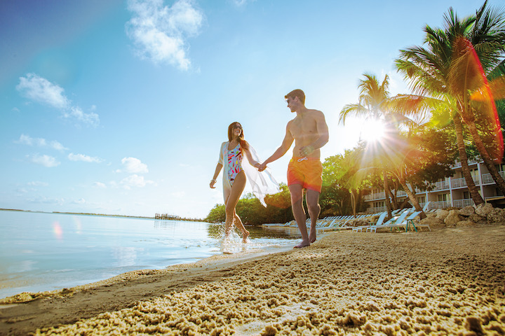 A couple holding hands on a beach in Key Largo