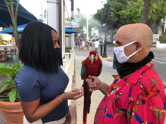 Sirena Jardines, is greeted by Ruby Red, a 44-year old Macaw, and her owner, Greg Scarza, on Duval Street in Key West, Tuesday evening. Photo by Rob O’Neal