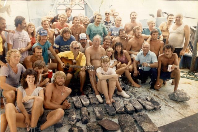One day after the July 20, 1985 discovery of the Atocha “Mother Lode,” singer-songwriter Jimmy Buffett and the late treasure hunter Mel Fisher sit perched on a throne of silver bars surrounded by family and “Golden Crew” members. Image: Pat Clyne