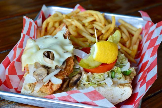 Hogfish Bar and Grill's Killer Hogfish Sandwich is a generous serving of fresh-caught hogfish topped with melted swiss cheese and sautéed mushrooms and onions — all nestled on a chunk of fresh Cuban bread with a side of crispy fries. 