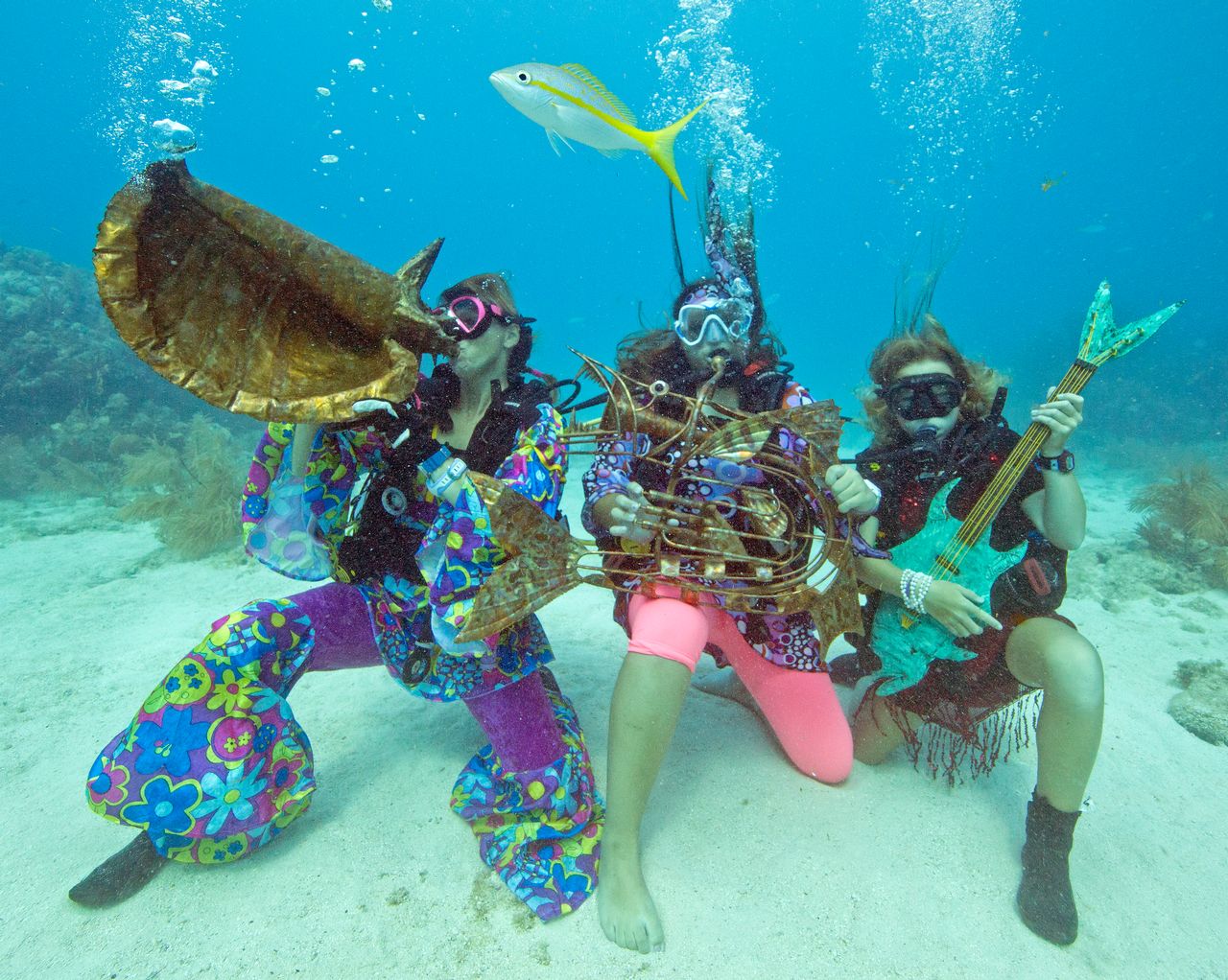 Costumed characters pretending to play musical instruments underwater seemingly play along to music piped underwater during the annual event. Photo: Bob Care