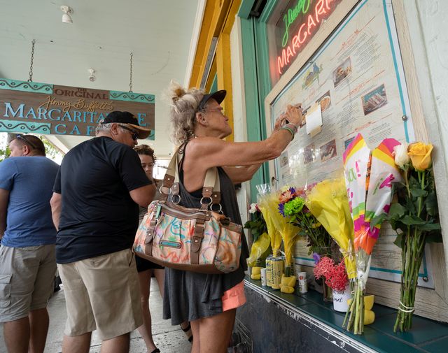 Susan Hudnall pins a condolence note about Jimmy Buffett’s passing to the front window of the Margaritaville Cafe in Key West. Photo: Rob O'Neal