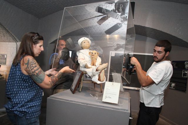 Key West Art & Historical Society staff tend to Robert the Doll's plexiglass exhibit case. Museum staff have reported creepy giggling in the museum. Photo: Carol Tedescco