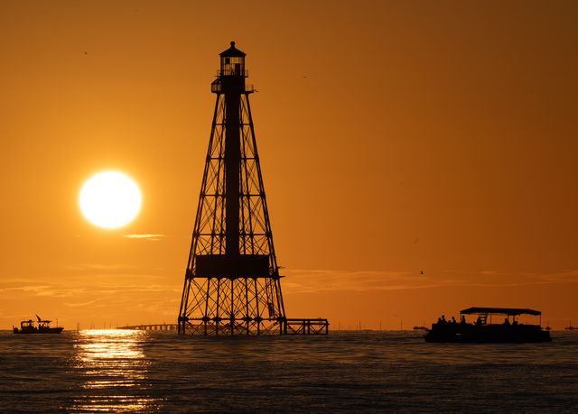 Boaters watch a sunset behind Alligator Reef Lighthouse. The beacon is named after a Navy schooner that ran aground in 1822 and sank on the reef. Photo: Andy Newman
