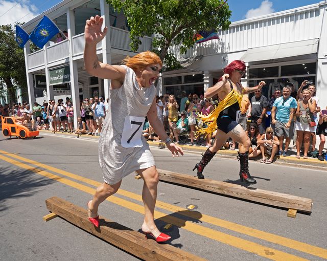 Competitors navigate precarious raised wood slats in high heels while fans cheer them on. 