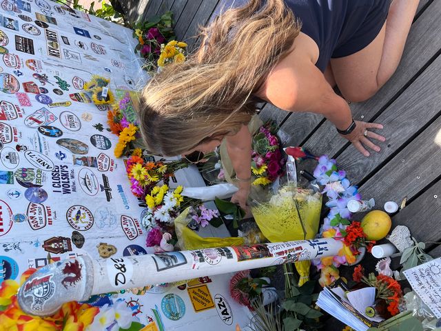 A fan places an orchid at the impromptu memorial outside Jimmy Buffett's Shrimp Boat Sound recording studio prior to the start of the 2023 second line memorial walking parade in Key West. Photo: Rob Modys