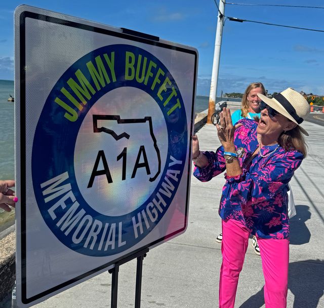 Lucy Buffett, sister of the late singer/songwriter Jimmy Buffett, admires a new Florida Department of Transportation sign designating state road A1A as the A1A Jimmy Buffett Memorial Highway.