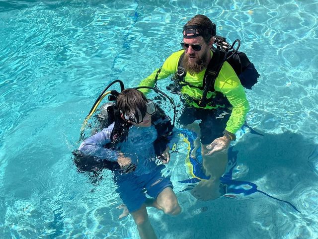 A diving instructor works in a pool with a young student on important elements of dive safety, understanding dive gear and more on the way to dive certification. Photo: Capt. Slate's Scuba Adventures