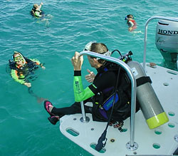 A power lift on Tranquility lowers a diver into the water as his HSA-certified dive buddy prepares to help.