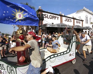 Teams of "strange bedfellows" propel decorated beds up a portion of Duval Street during the Conch Republic Red Ribbon Bed Race.